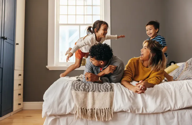 family laughing and jumping on bed